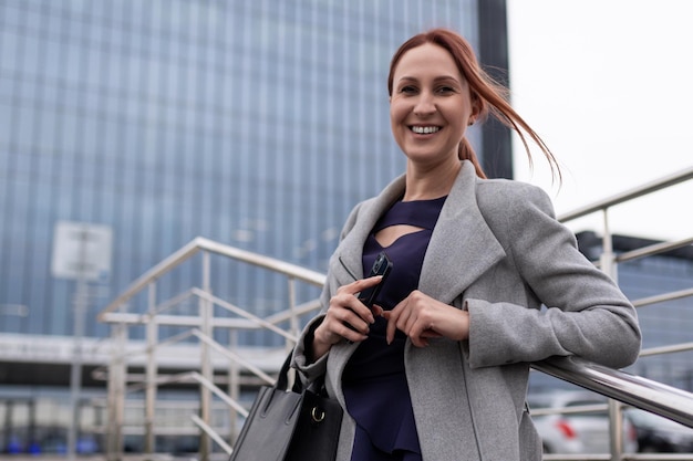 Mulher de negócios ruiva confiante satisfeita com um sorriso largo olha para a câmera no fundo