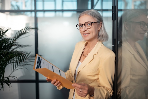 Foto mulher de negócios satisfeita. closeup retrato de uma mulher de negócios satisfeita usando óculos, segurando uma pasta de papel enquanto olha para a frente dela