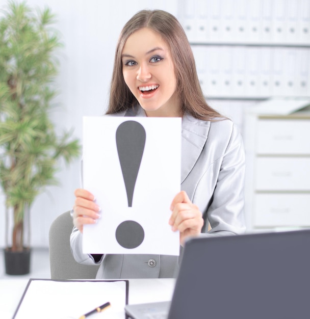 Mulher de negócios segurando o ponto de exclamação sentado atrás de uma mesa