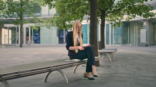 Foto mulher de negócios segurando um tablet digital sentada em um banco ao ar livre