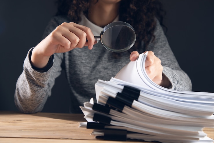 Foto mulher de negócios segurando uma lupa e documentos