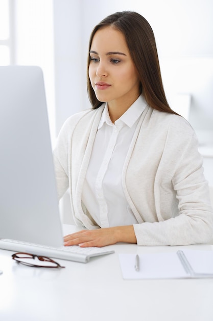 Mulher de negócios sentada e trabalhando com computador no escritório branco