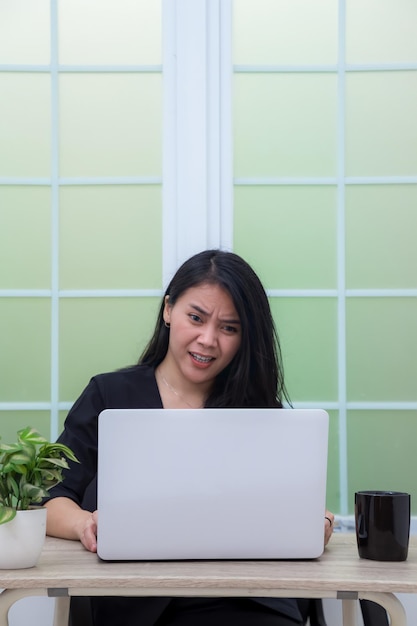 Mulher de negócios sentada na cadeira da mesa de escritório com expressão facial de raiva