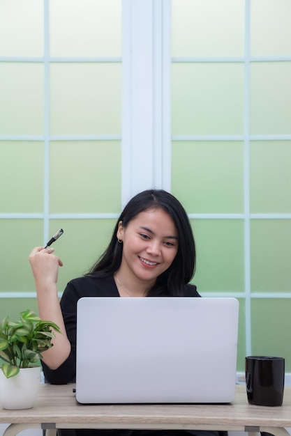 Mulher de negócios sentada na cadeira na sala de escritório trabalhando com laptop