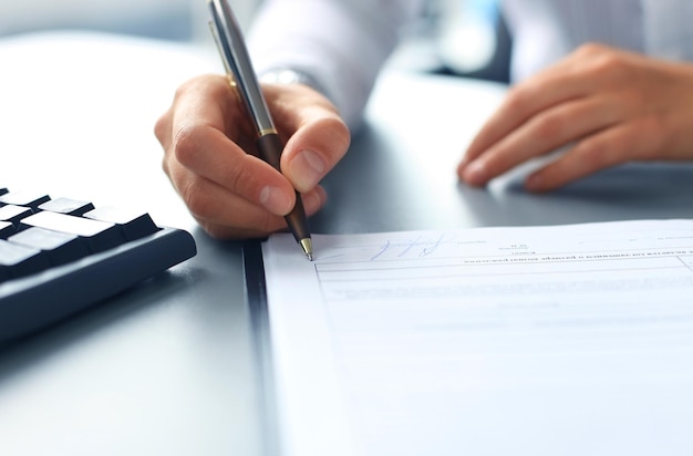 Mulher de negócios sentada na mesa do escritório, assinando um contrato com foco superficial na assinatura.