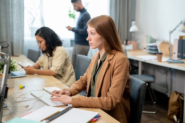 Mulher de negócios séria se concentrando na rede em frente ao monitor do computador