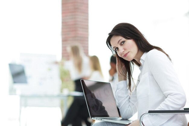 Mulher de negócios sorridente com laptop em fundo desfocado