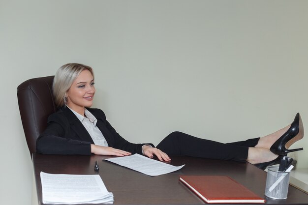 Mulher de negócios sorridente com o pé na mesa