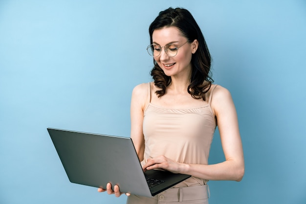 Mulher de negócios sorridente em copos trabalhando no laptop.