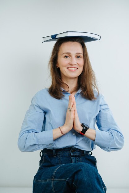 Mulher de negócios sorridente engraçada meditando com um diário em cima da cabeça