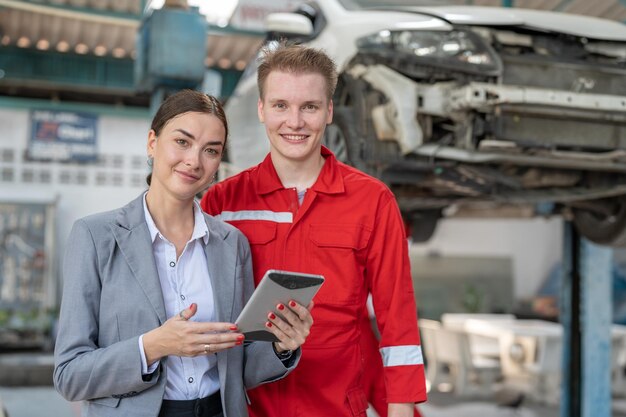 Foto mulher de negócios sorridente proprietária e mecânica homem serviço de reparação e manutenção de carros no serviço de garagem