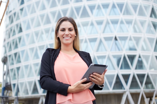Foto mulher de negócios sorridente segurando um tablet digital em ambiente urbano
