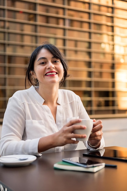 Mulher de negócios sorridente trabalhando e bebendo café no terraço de uma cafeteria, conceito de empreendedor digital e estilo de vida urbano, cópia espaço para texto