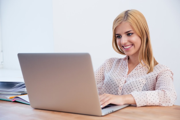 Mulher de negócios sorridente usando laptop no escritório