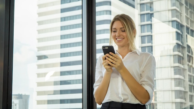 Mulher de negócios sorridente usando telefone celular no escritório