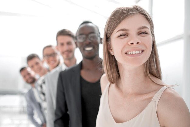 Mulher de negócios sorrindo na frente da equipe corporativa juntos olhando para a câmera no escritório da empresa