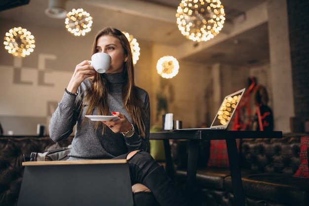 Mulher de negócios tomando café em um café e trabalhando em um laptop