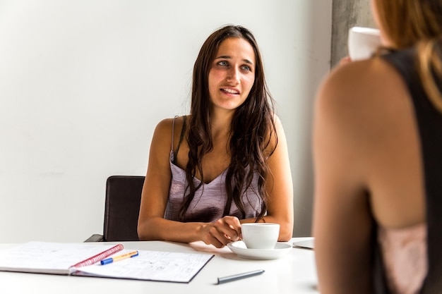 Foto mulher de negócios tomando café enquanto discute com uma colega no escritório