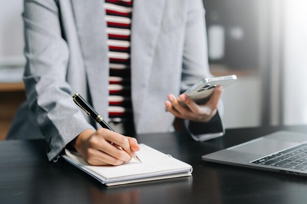 Mulher de negócios trabalhando com um novo computador moderno e escrevendo na estratégia do bloco de notas