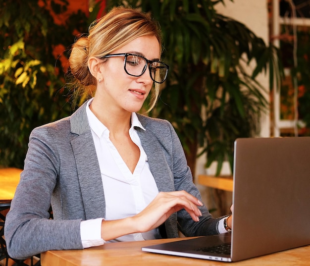 Mulher de negócios trabalhando no laptop na cafeteria Jovem empresária usa laptop no caféEstilo de vida e conceito de negócios