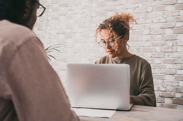 Mulher de negócios trabalhando no laptop na mesa na frente de um homem visto de trás Conceito de empresária e cliente Pessoas trabalhando juntas em equipe Profissional do sexo feminino com computador online