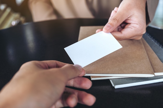 Mulher de negócios troca cartão de visita com notebooks na mesa do escritório