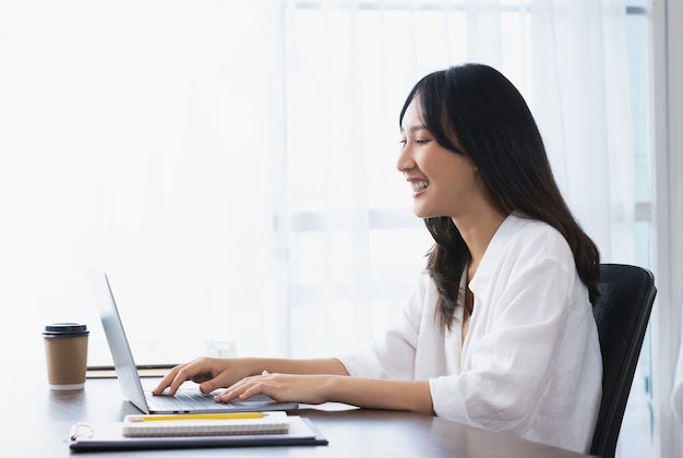 Mulher de negócios usando laptop e sentado à mesa no escritório em casa.