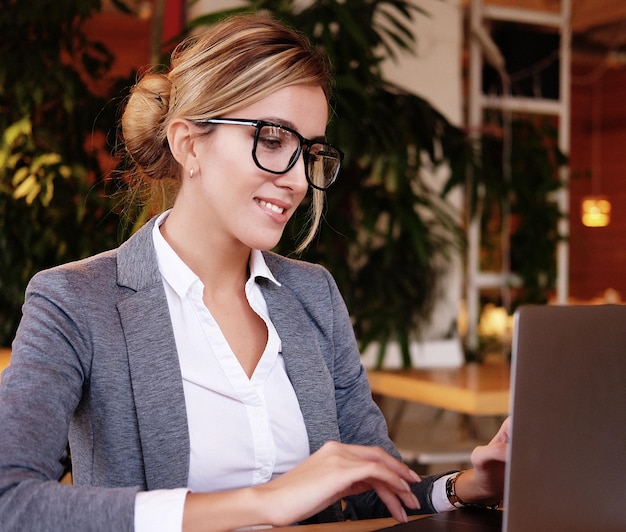 Mulher de negócios usando laptop no café Jovem linda sentada em uma cafeteria e trabalhando no computador