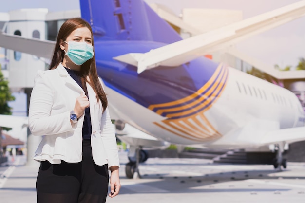 Foto mulher de negócios usando máscara enquanto está de pé ao lado do avião