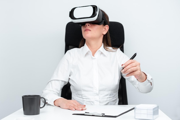 Mulher de negócios usando óculos de realidade virtual e aprendendo habilidades profissionais através de simulação futurista Mulher segurando caneta e sentado na mesa durante o treinamento moderno