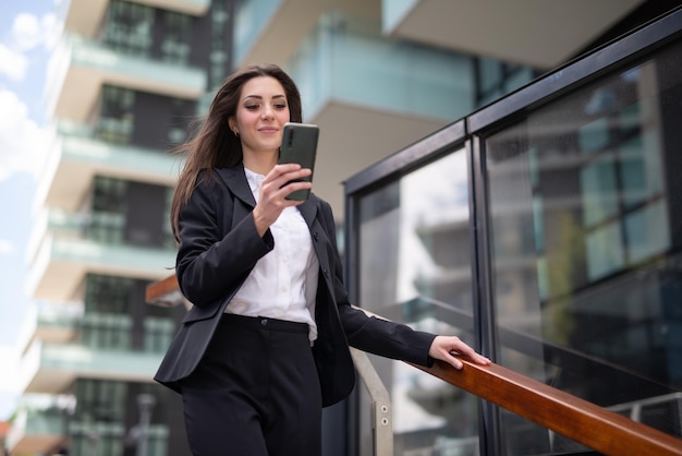 Mulher de negócios usando seu smartphone enquanto descia as escadas em uma cidade moderna