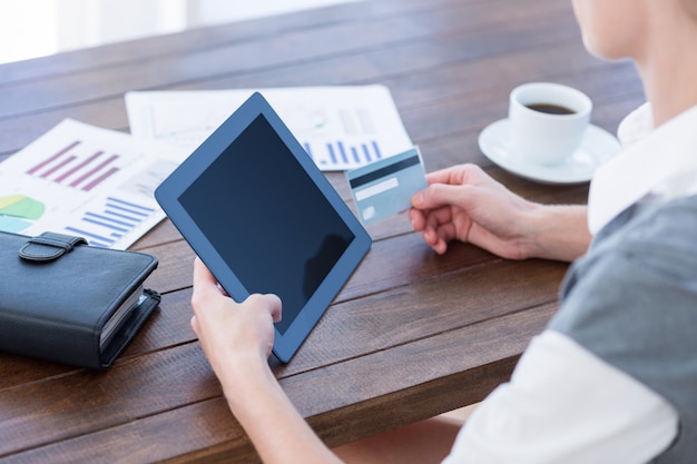 Mulher de negócios usando tablet pc e segurando cartão de crédito