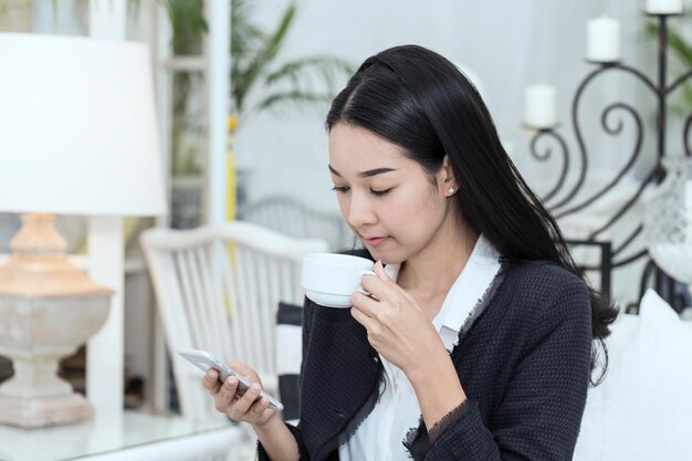 Mulher de negócios usando telefone celular enquanto bebe café