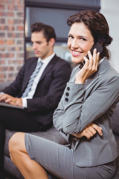 Mulher de negócios usando telefone celular enquanto colega