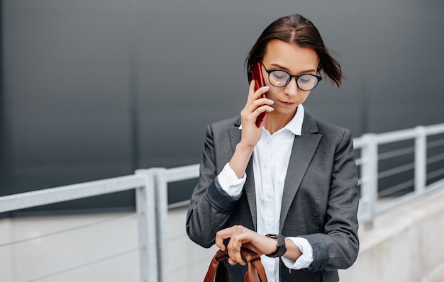 Mulher de negócios verifica a hora na cidade durante um dia útil à espera de uma reunião. Disciplina e tempo. Um funcionário vai para uma reunião corporativa.