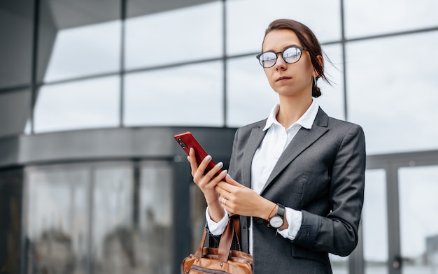 Mulher de negócios verifica a hora na cidade durante um dia útil à espera de uma reunião. Disciplina e tempo. Um funcionário vai para uma reunião corporativa.