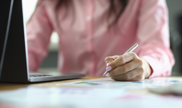 Mulher de negócios verifica dados no relatório e no laptop