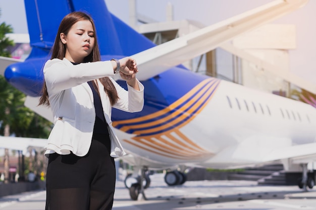 Mulher de negócios verificando a hora enquanto está de pé perto do avião