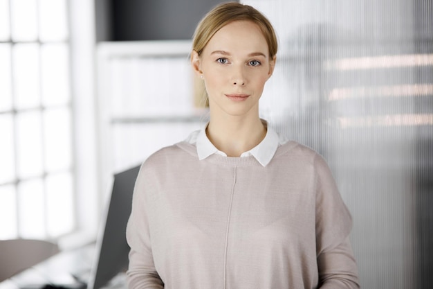 Mulher de negócios vestida casual adulta amigável em pé em linha reta. Headshot de negócios ou retrato no escritório.