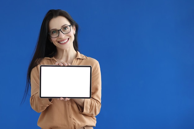 Mulher de óculos segurando um tablet digital com tela branca nas mãos