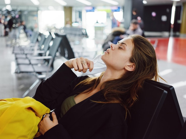 Mulher de olhos fechados sentada no aeroporto esperando bagagem de voo