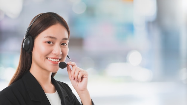 Mulher de operador de serviço ao cliente asiático com fone de ouvido de microfone trabalhando em plano de fundo de espaço de escritório de contato de centro de atendimento.