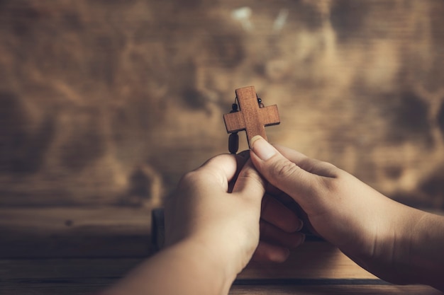 Mulher de oração segurando uma cruz na bíblia