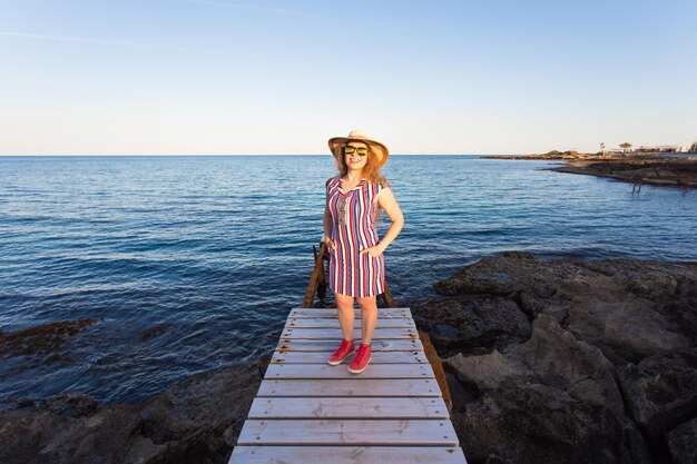 Foto mulher de pé ao lado do mar contra o céu claro