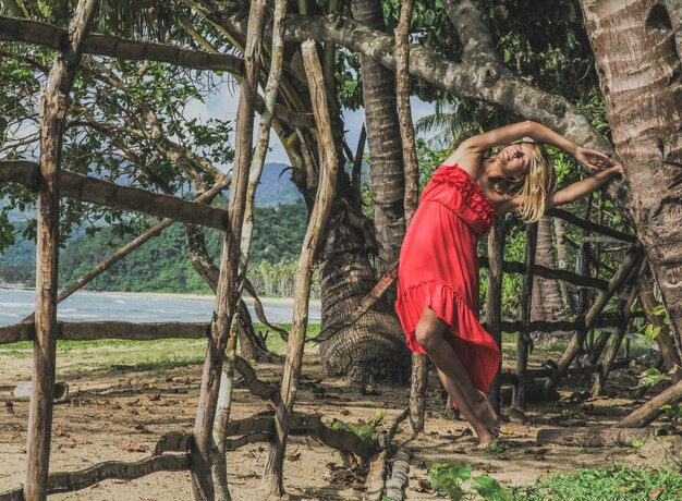 Foto mulher de pé ao lado do tronco de uma árvore na floresta