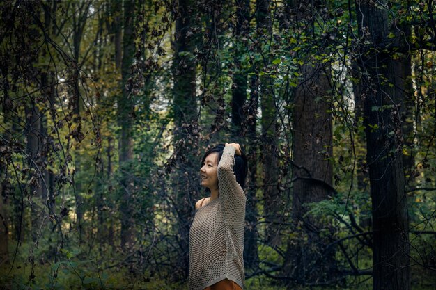 Mulher de pé ao lado do tronco de uma árvore na floresta