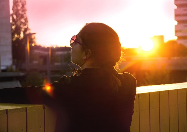 Foto mulher de pé contra o sol durante o pôr do sol