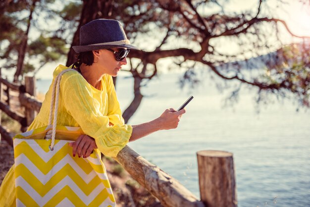 Mulher de pé em uma cerca de madeira e usando telefone inteligente