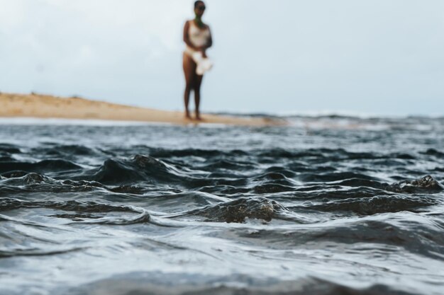 Mulher de pé na costa na praia contra o céu