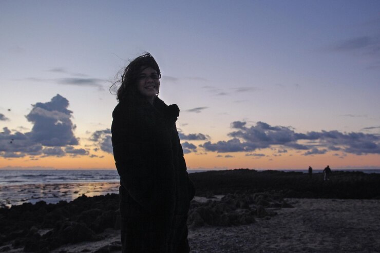 Foto mulher de pé na praia contra o céu durante o pôr do sol